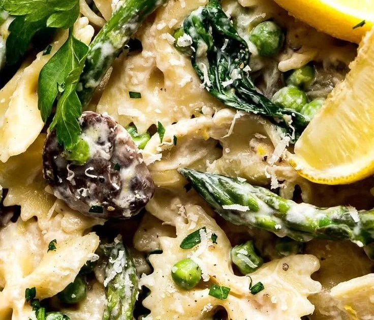 Creamy lemon asparagus pasta dish garnished with herbs and lemon zest.
