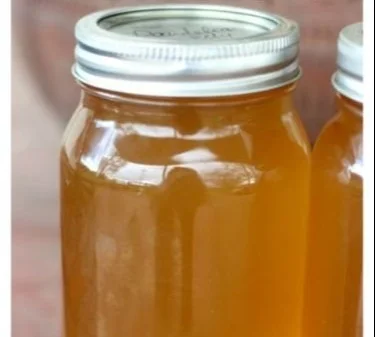 Homemade dandelion jelly in a jar with flowers and bread