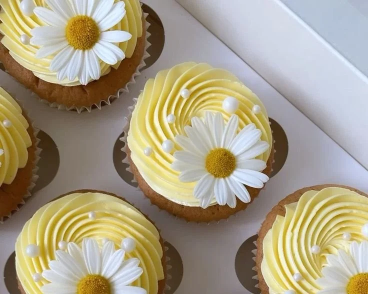 Pastel yellow cupcakes decorated with daisies and pearls