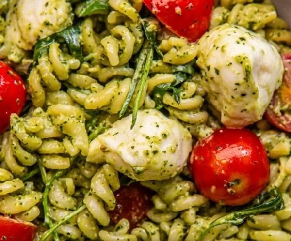 Colorful pesto pasta salad with fresh vegetables and a vibrant dressing