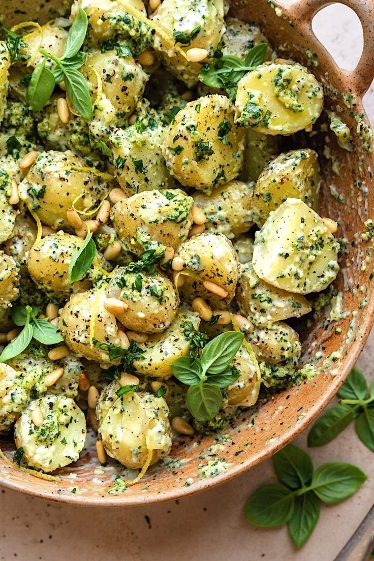 Delicious pesto potato salad served in a bowl with fresh basil and cherry tomatoes.