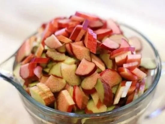 Homemade rhubarb cinnamon jam in a jar with fresh rhubarb stalks.