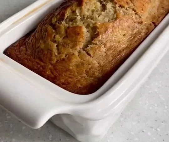 Sliced rustic Tuscan banana bread displayed on a wooden cutting board.